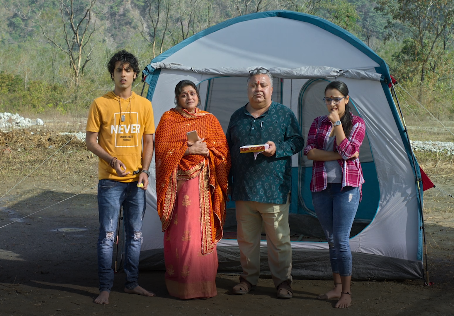 A family of four looking stressed while standing in front of a tent