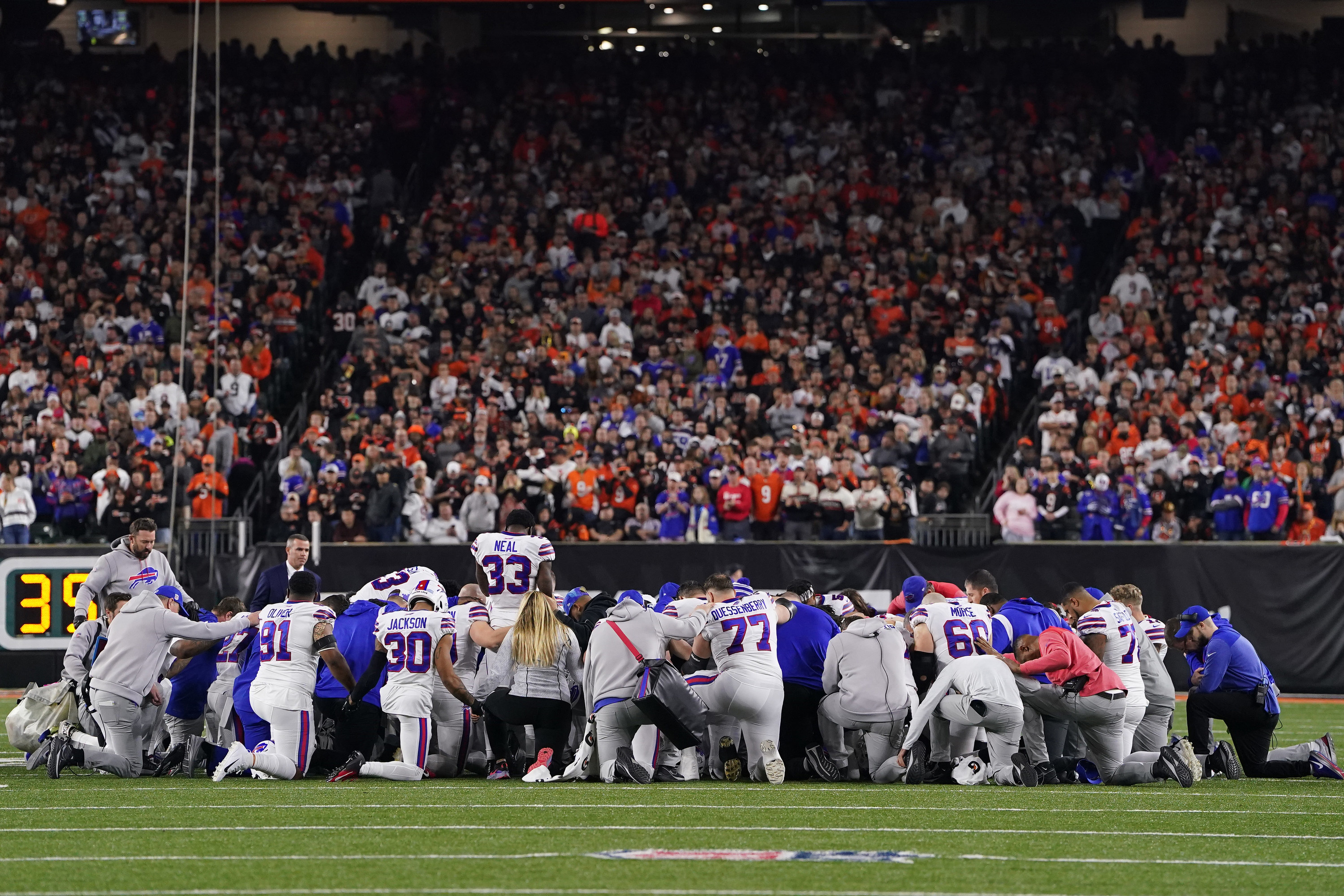 Buffalo Bills players huddle and pray after teammate Damar Hamlin collapsed on the field