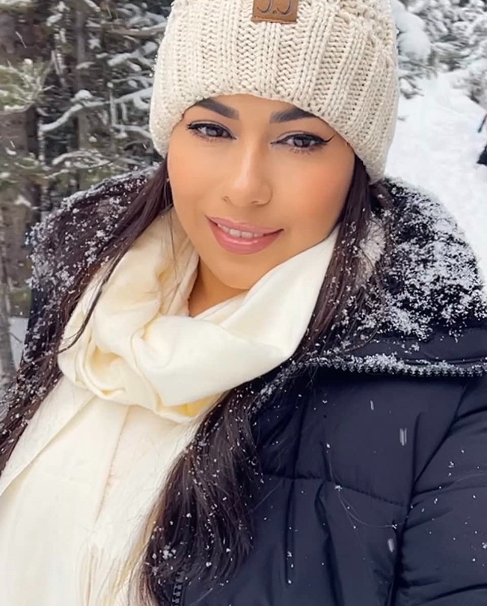 a reviewer wearing the cream colored knit beanie in the snow