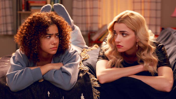 Ginny and Georgia look at each other as they both lay on their stomachs side-by-side in a promo photo for the show