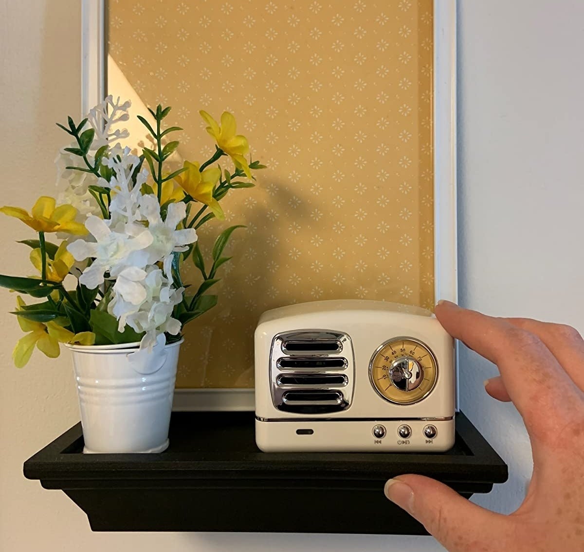 reviewer image of the white speaker on a wall-mounted shelf