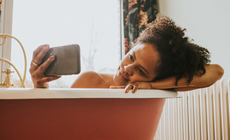 A girl laying in the tub on her phone