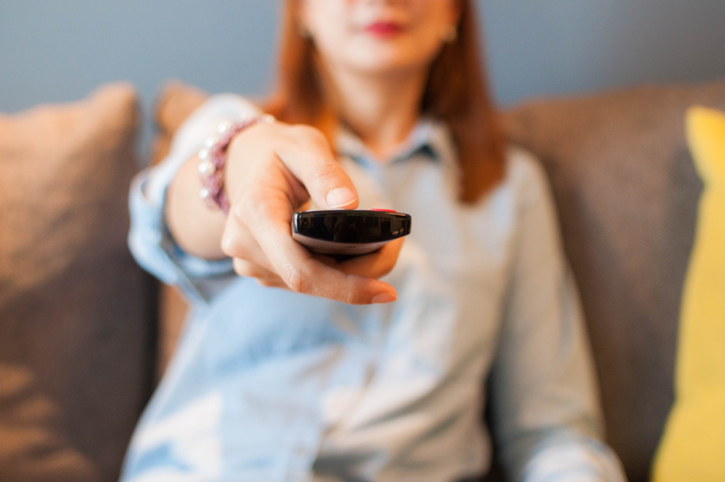 A woman pointing a remote at the camera