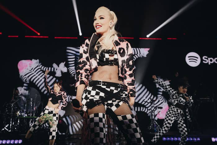 Gwen smiles as she performs onstage with backup dancers behind her
