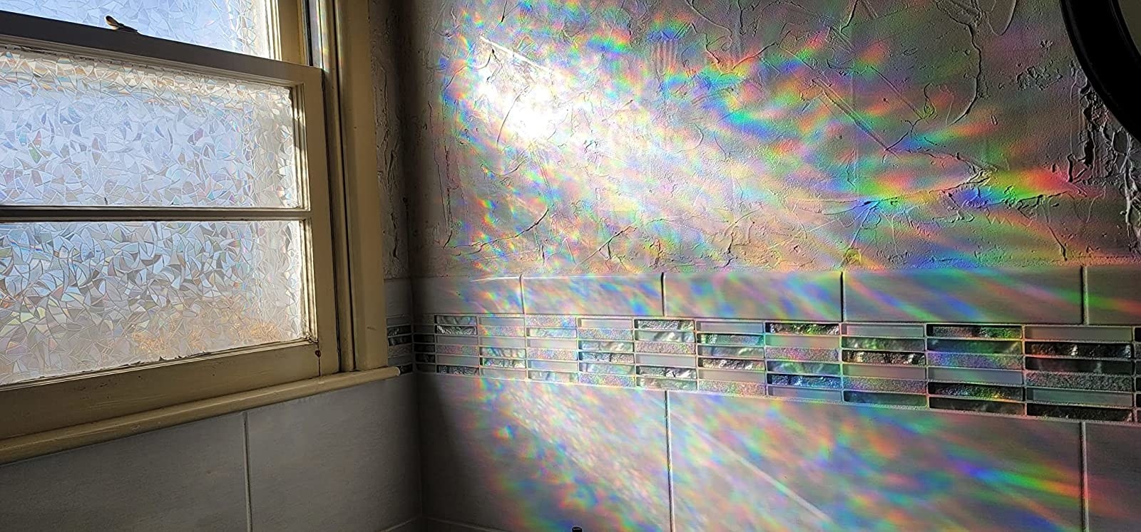 Reviewer&#x27;s rainbow refracting window film casting rainbow onto the wall