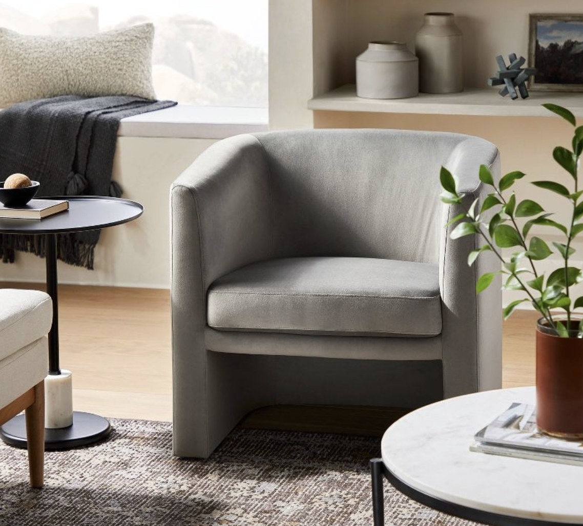 A grey accent chair on a grey rug