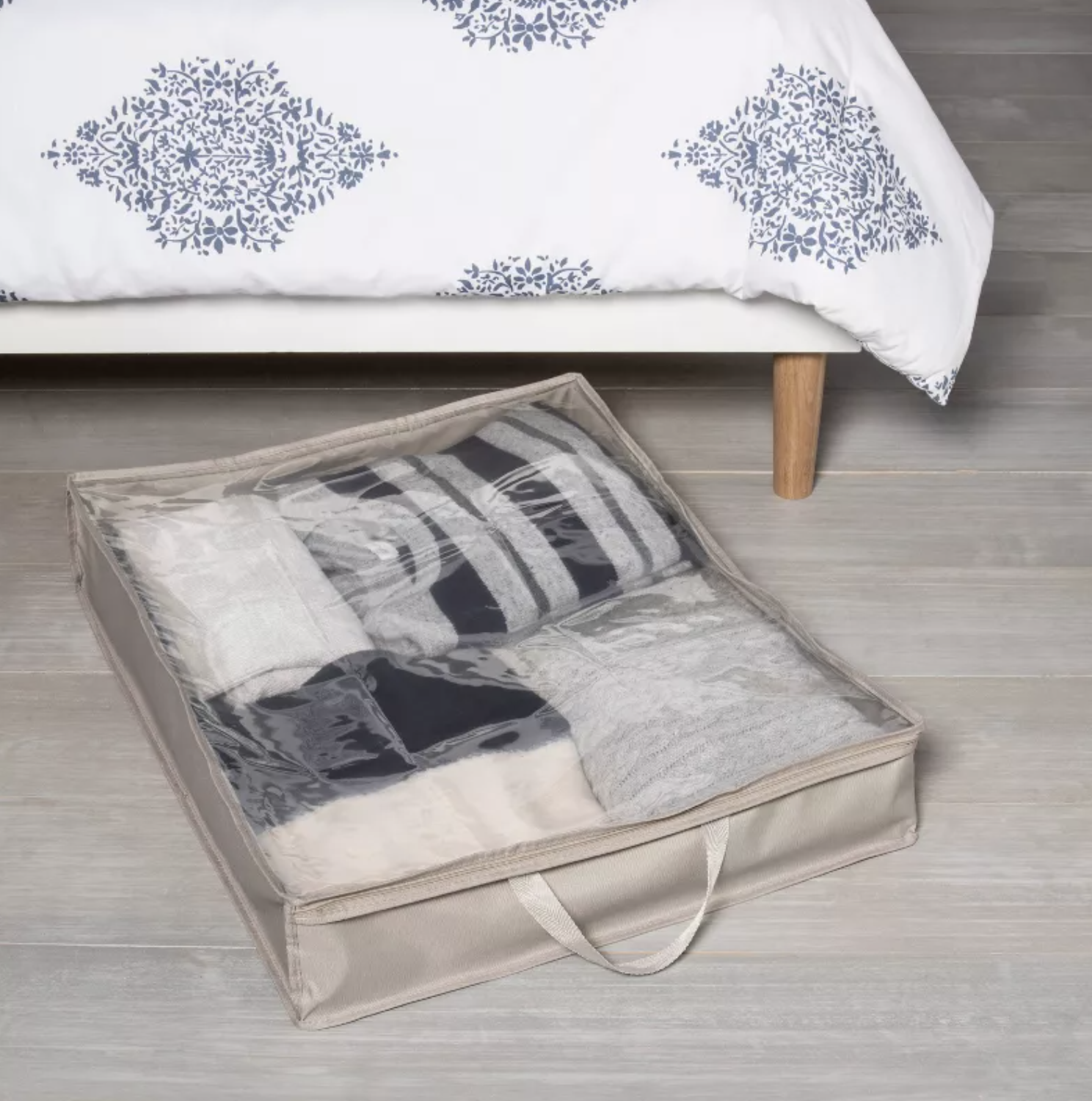 storage box with clothes inside right next to a bed it can fit underneath