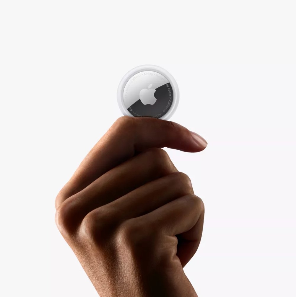 a model holding the round silver tracker with the apple logo