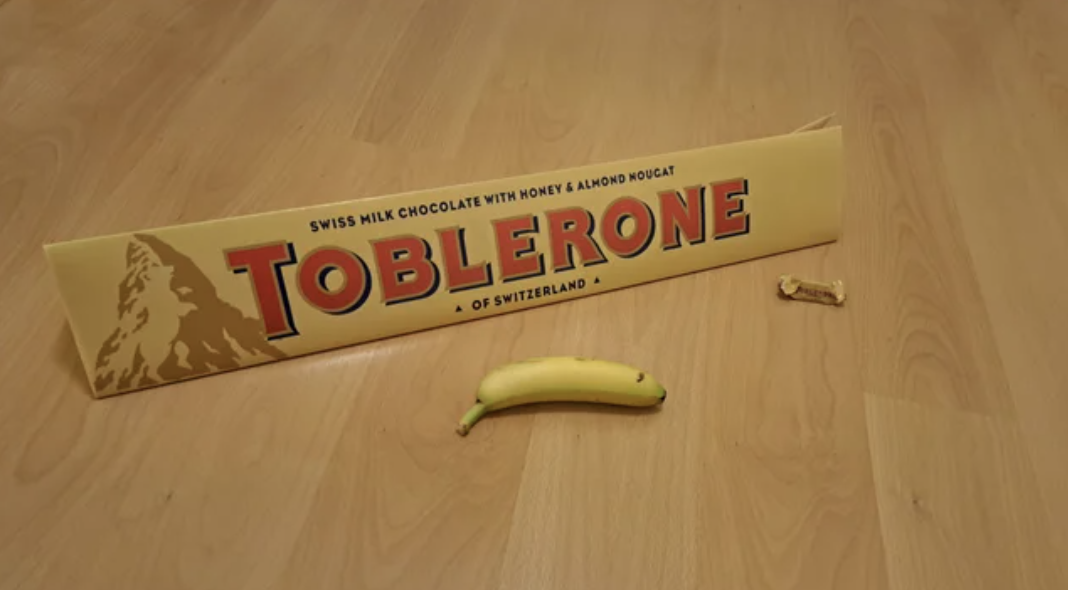 A Toblerone several times larger than the banana next to it