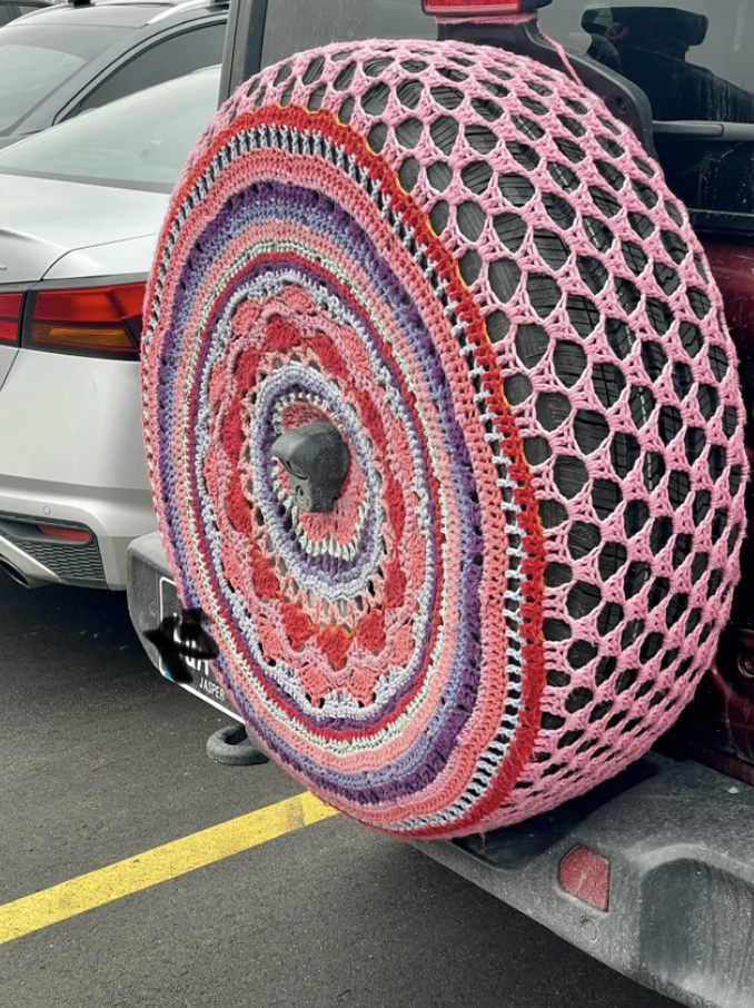 A multicolored crocheted cover on a tire