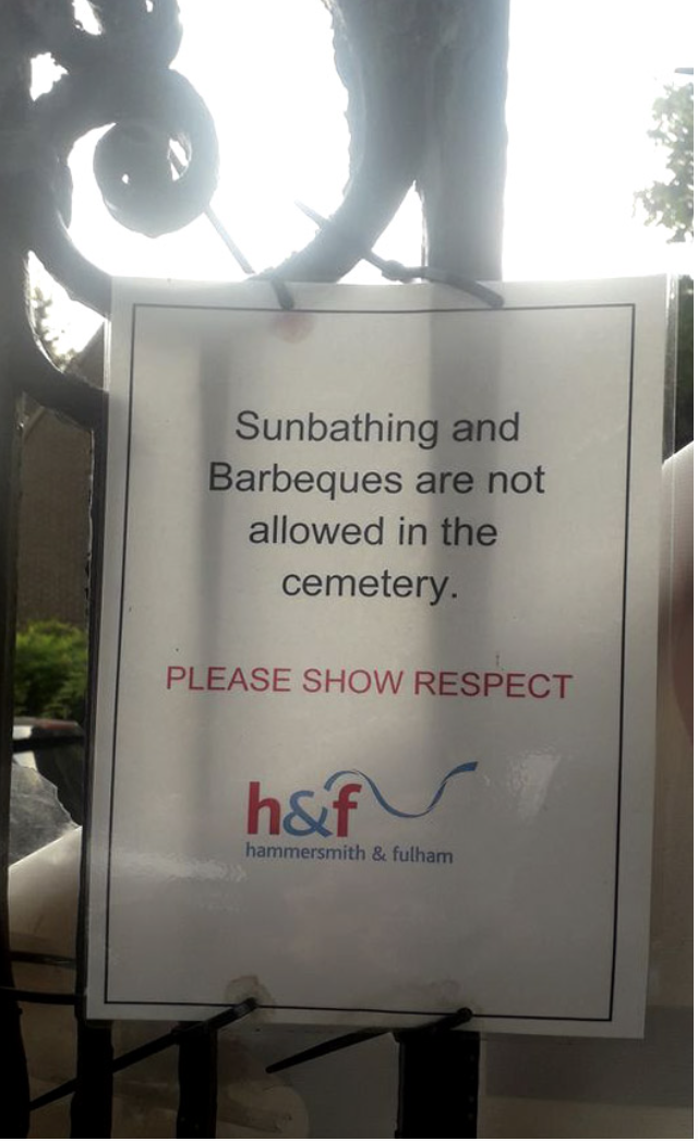 A sign saying sunbathing and barbecuing are not allowed in the cemetery and asking people to show respect