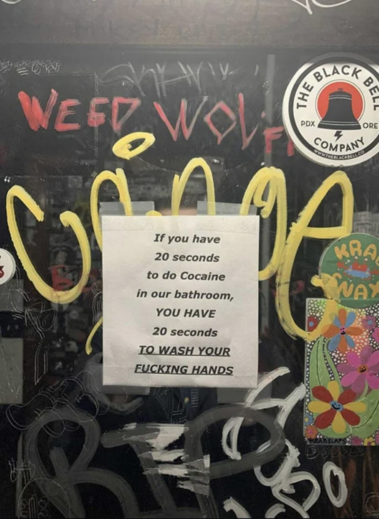 A sign on a wall covered in graffiti says &quot;if you have 20 seconds to do cocaine in our bathroom, you have 20 seconds to wash your fucking hands&quot;