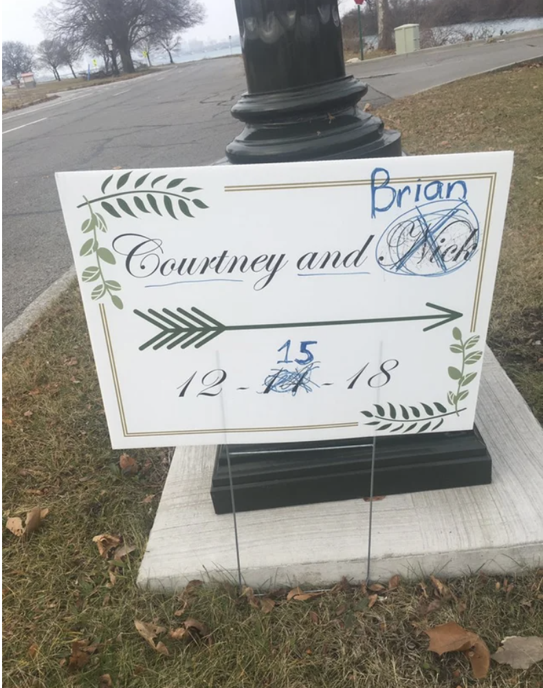 A sign for a wedding has the groom&#x27;s name crossed out and replaced, as well as the date rewritten from the 11th to the 15th