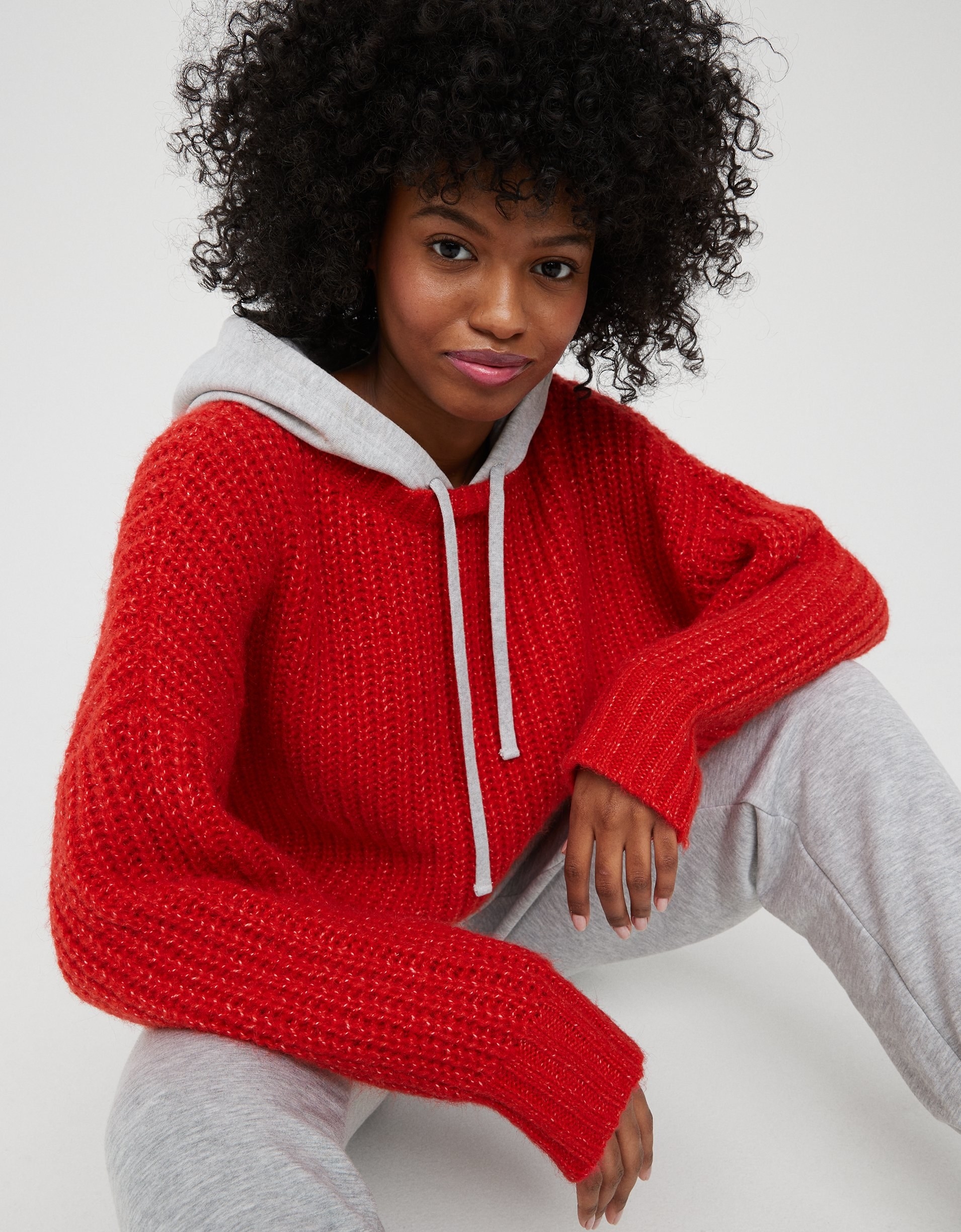 model in red ribbed sweater with a grey cotton hood and drawstrings