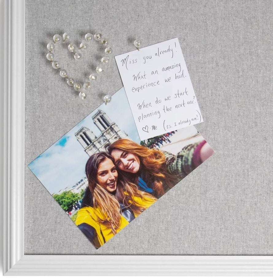 The clear round pushpins making a heart securing a picture on a bulletin board