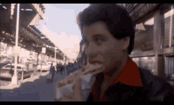 John Travolta eating pizza while walking in Saturday Night Fever