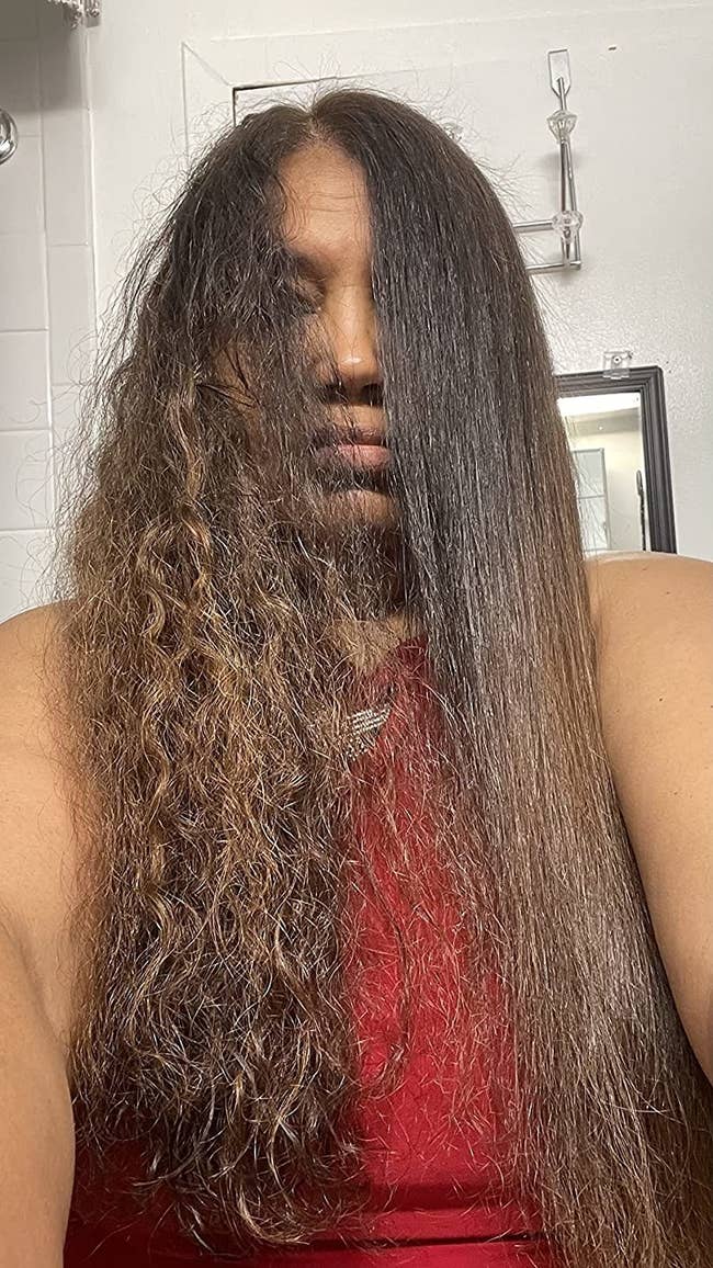 reviewer with half of hair curly and the other half silky straight using anti-frizz treatment