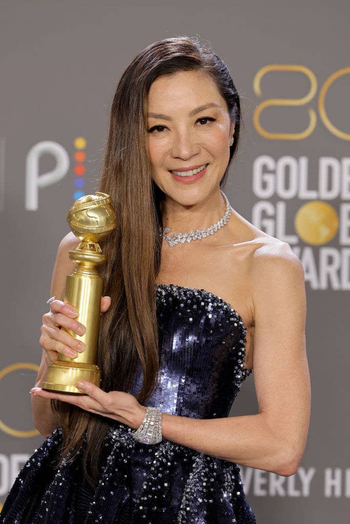 Michelle smiles as she holds up her awards backstage