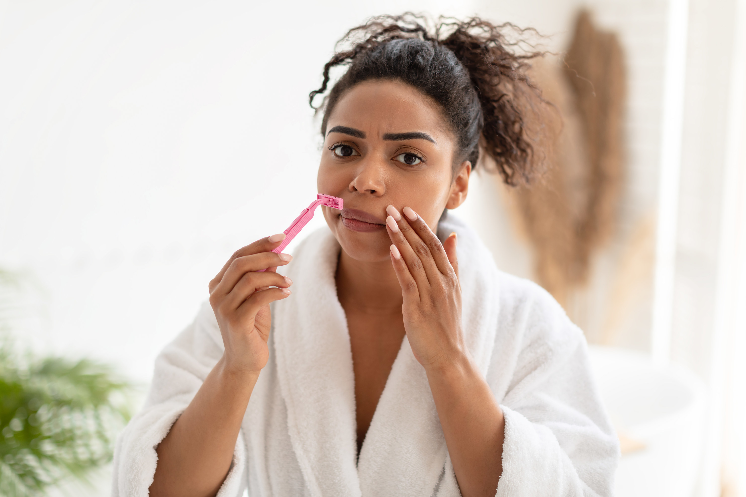 a woman in a bathrobe shaving her face