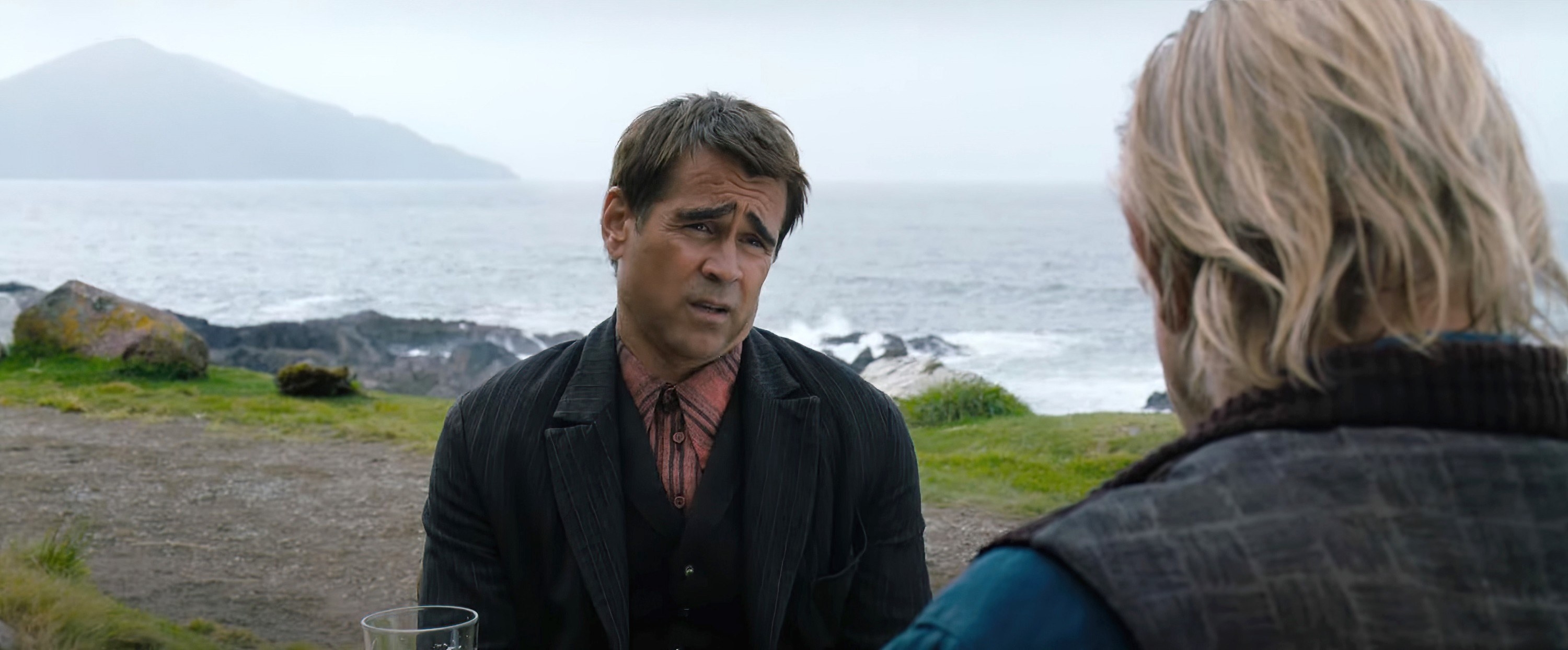 Colin Farrell sits talking to Brendan Gleeson by the sea