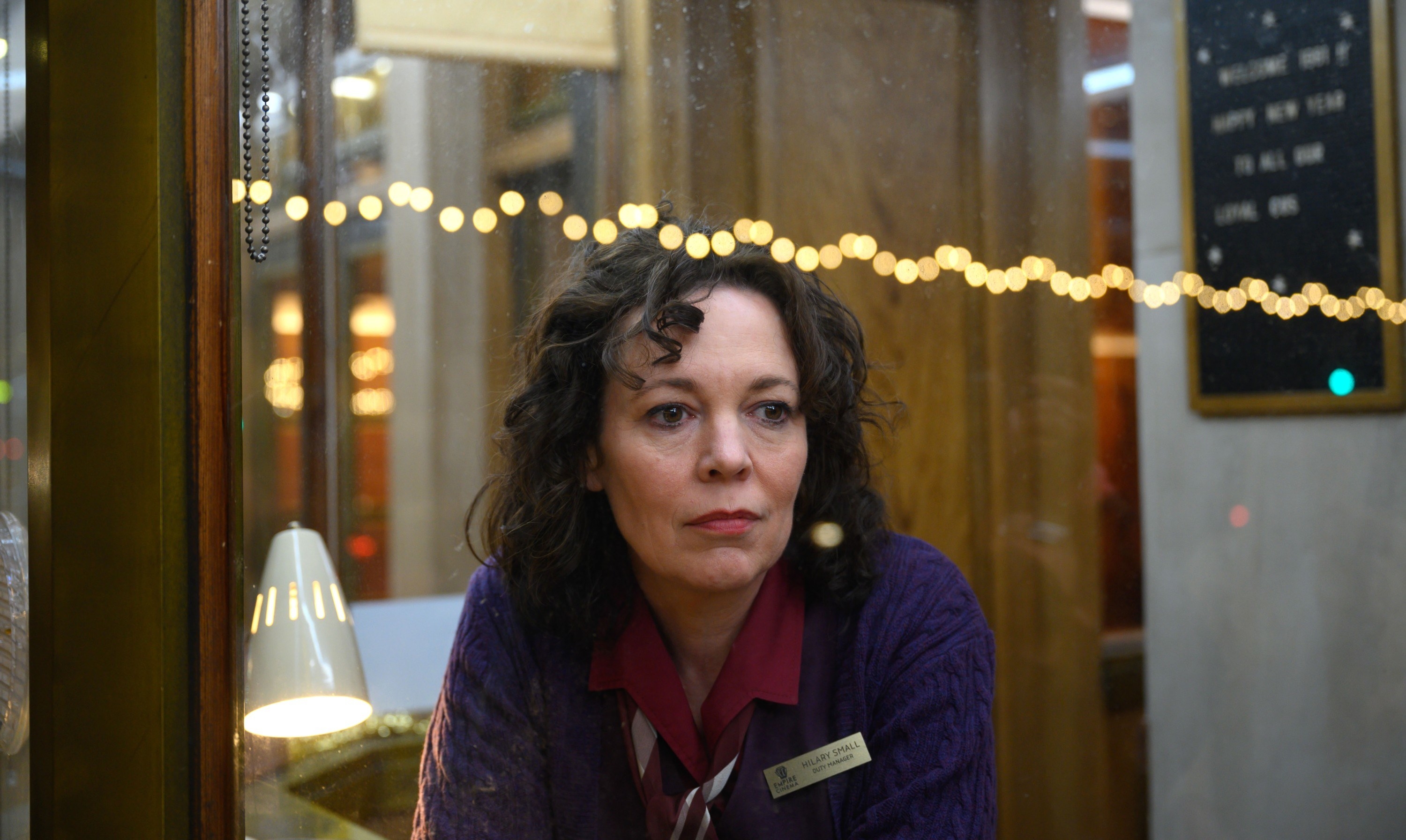Olivia Colman sit in a ticket booth