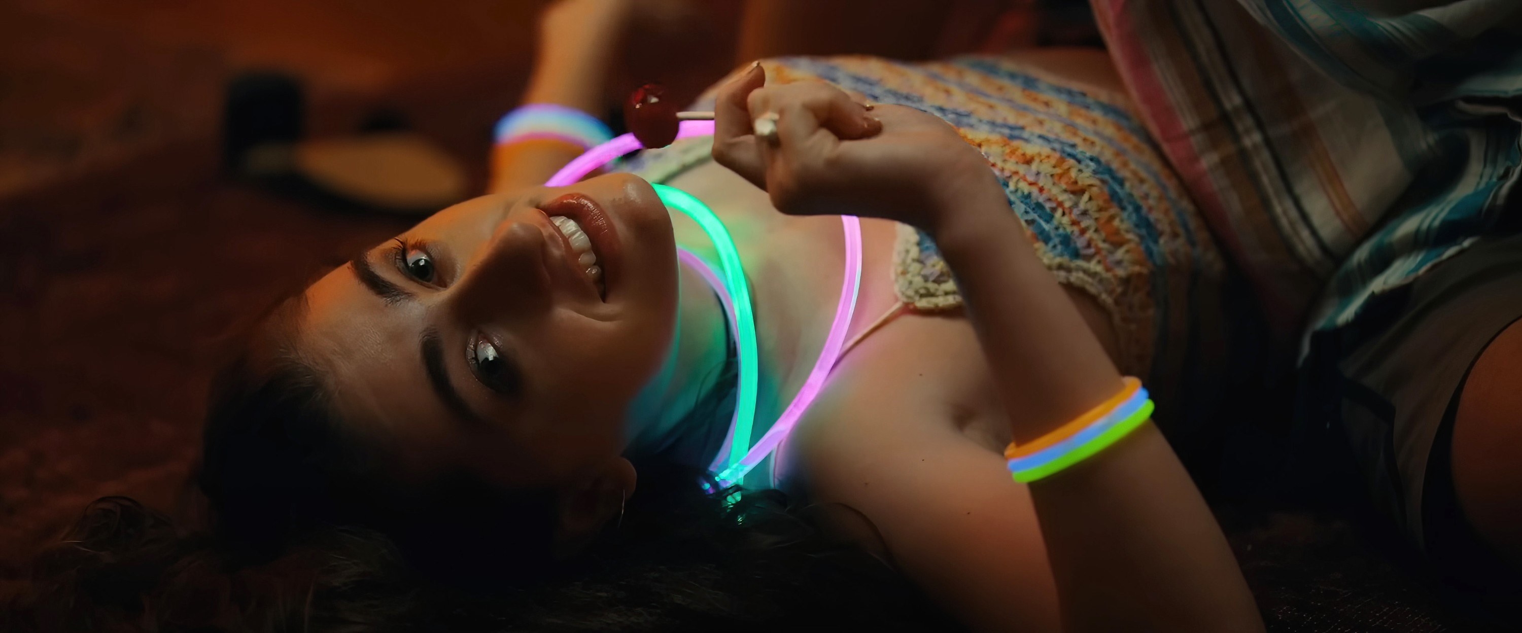 Rachel Sennott lays on the floor wearing glow in the dark necklaces