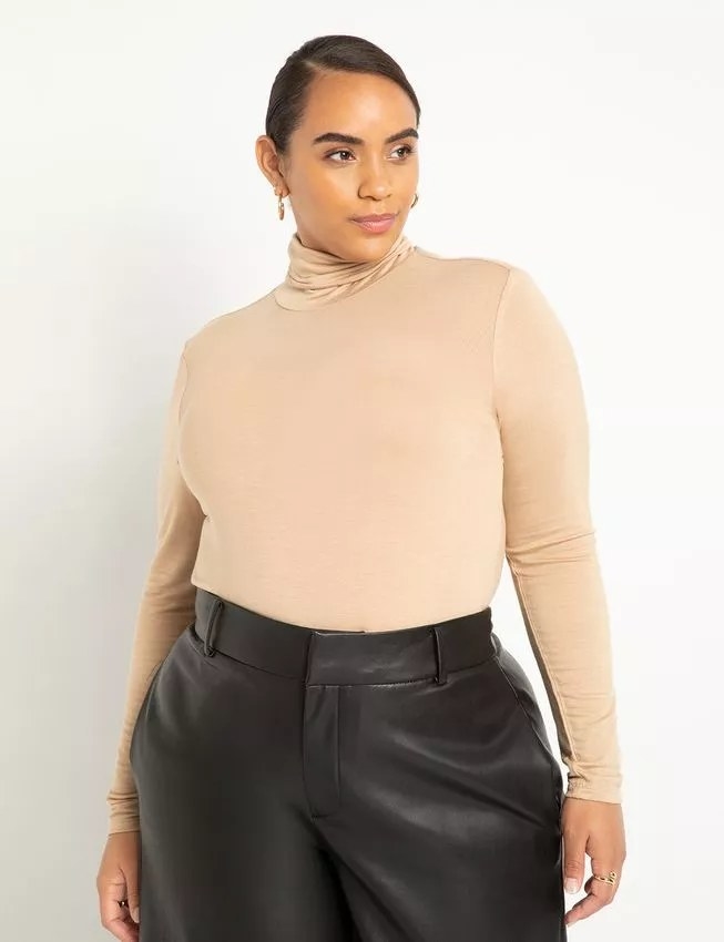 Model wearing beige turtleneck with black skirt