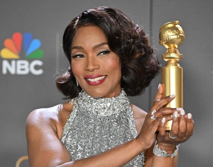 Angela smiles as she holds up her second Golden Globe Award with both hands