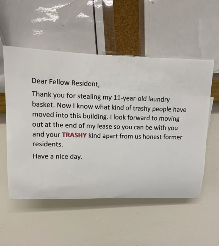 A letter taped to a wall says "dear fellow resident, thank you for stealing my 11-year-old laundry basket, now I know what kind of trashy people have moved into this building"