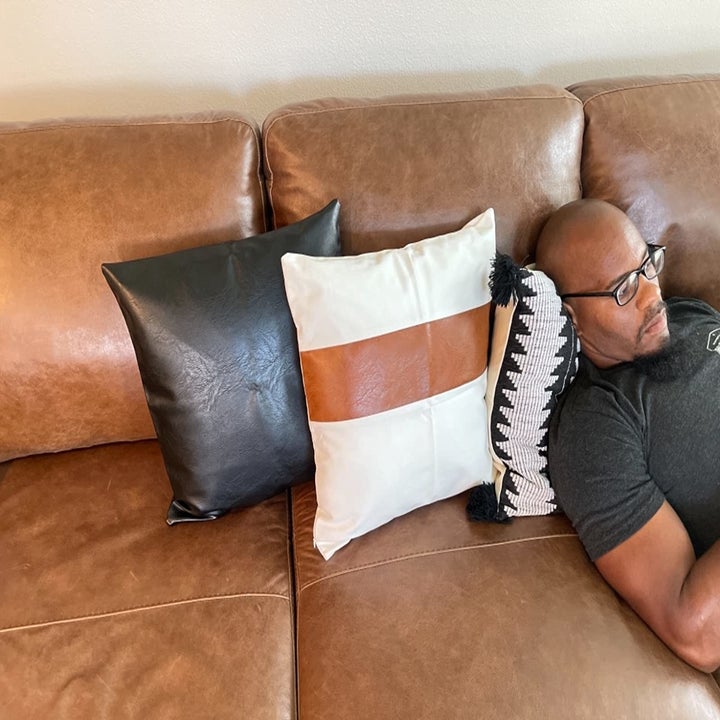 A reviewer laying on their couch on the pillows