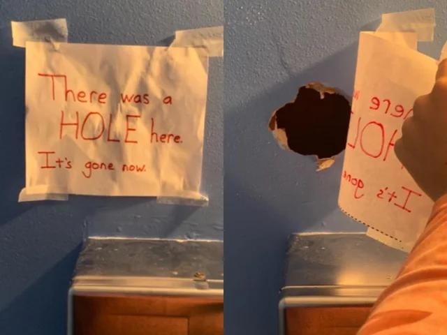 Handwritten sign &quot;There was a hole here; it&#x27;s gone now&quot; on a wall above a sink