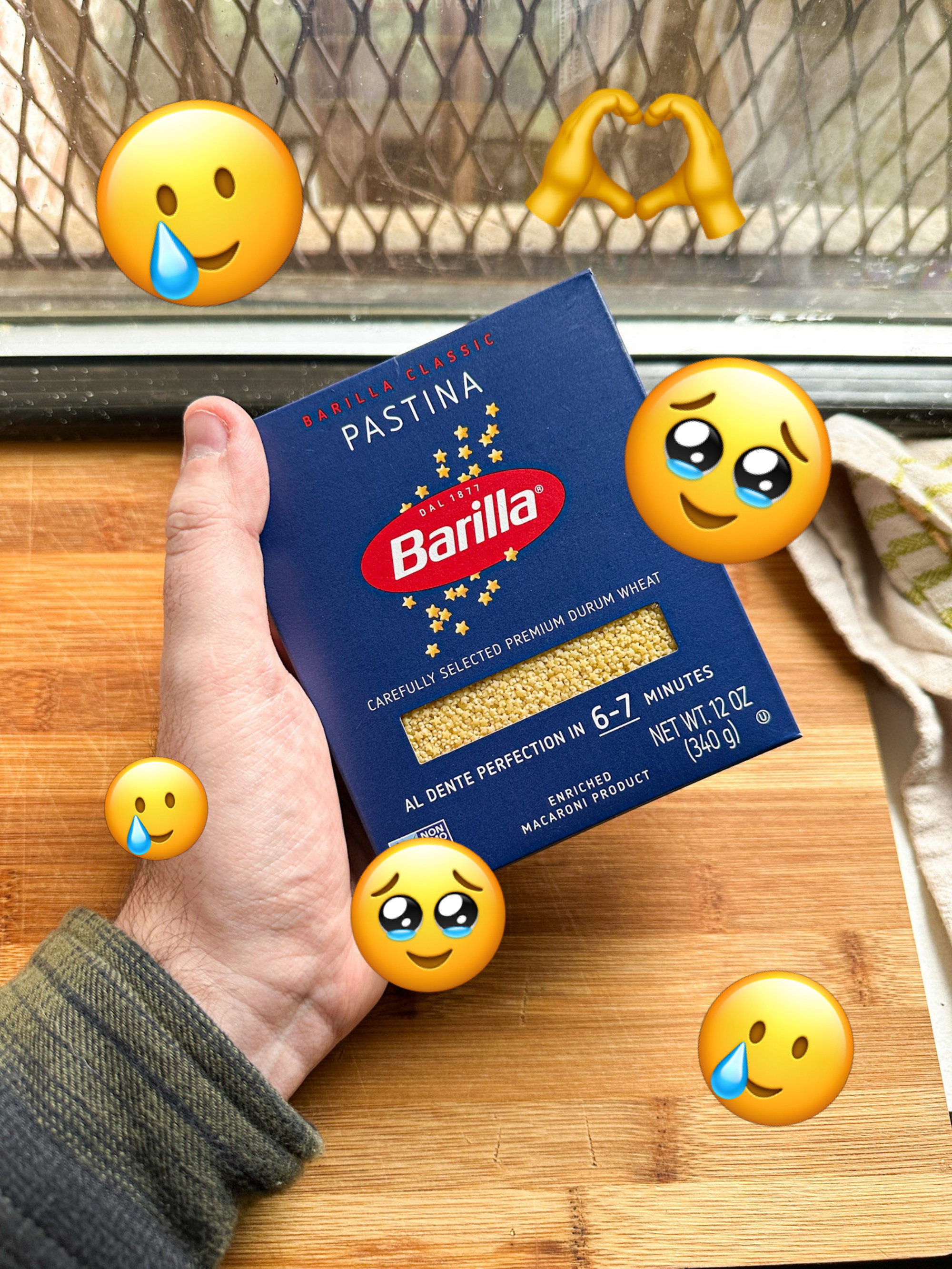 author holding box of Barilla brand pastina with happy crying emojis all around it