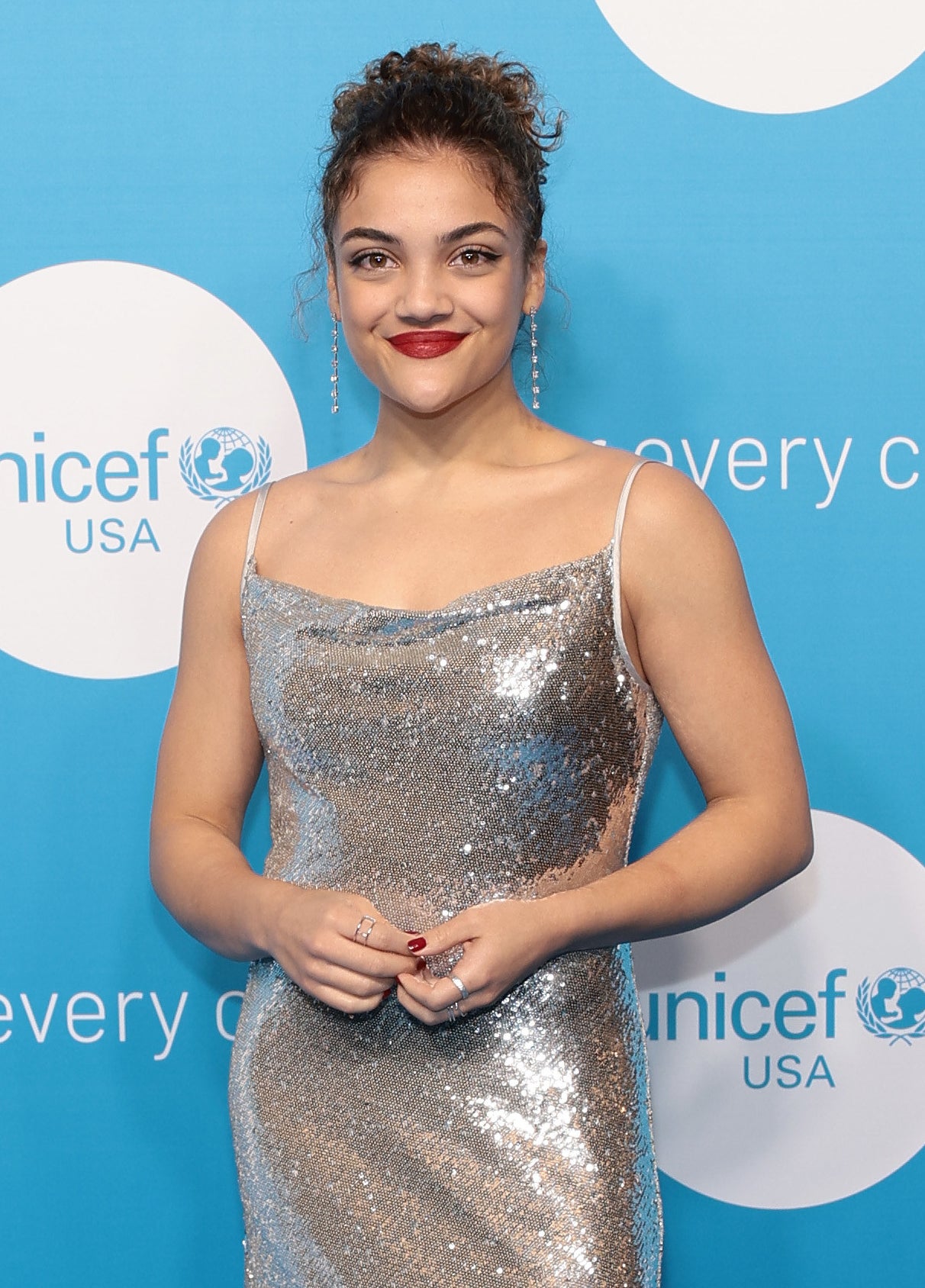 Laurie smiling on the red carpet in a shiny, spaghetti-strap dress