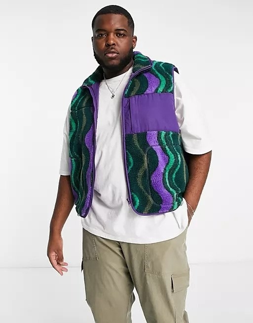 Model wearing green and purple wavy patterned teddy vest over white tee