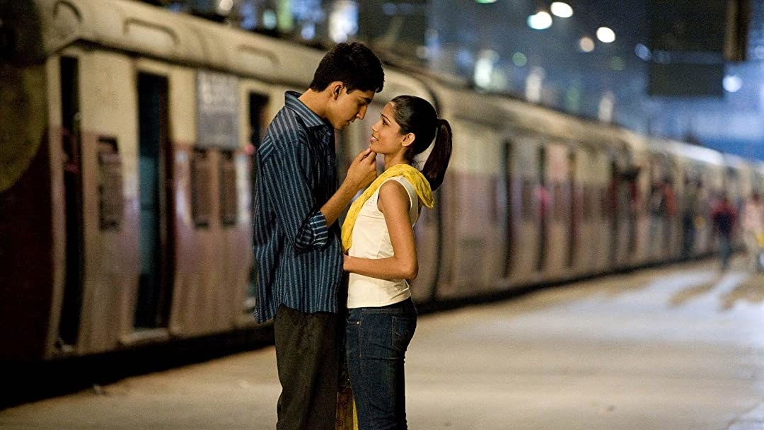 A man cradles a woman's face while they're at a railway station