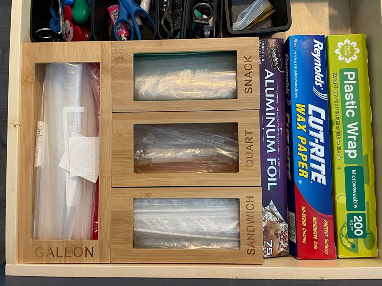 A reviewer&#x27;s wooden storage boxes, each engraved with &quot;gallon, sandwich, quart, or snack&quot; and filled with baggies in a drawer