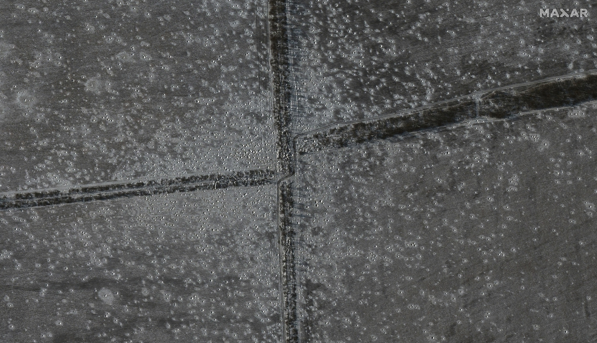 A satellite image of open fields with tons of craters freckling the ground