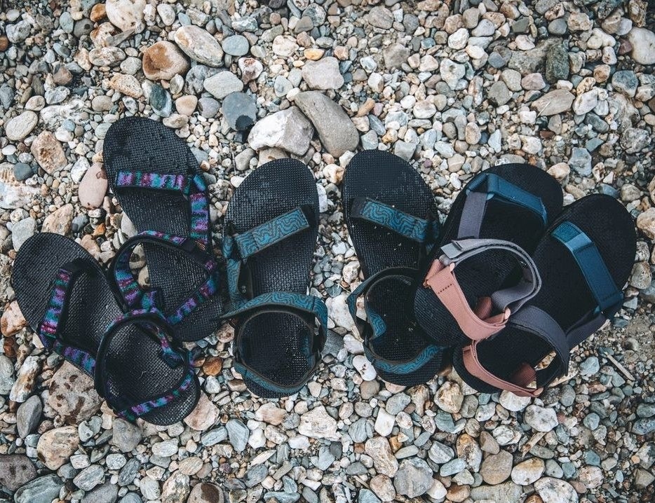 three pairs of teva sandals on a bed of rocks