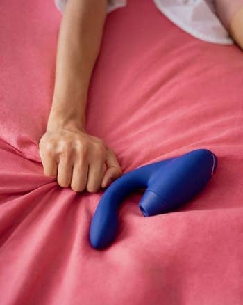 Hand grabbing sheets with blue dual-stimulating vibrator