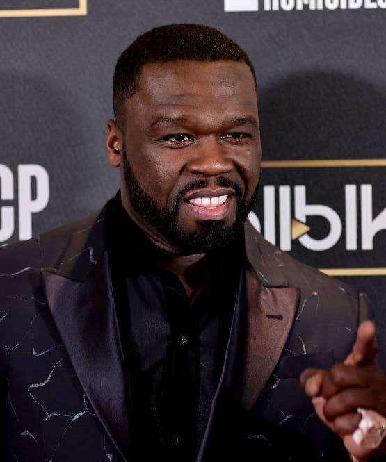A closeup of 50 Cent pointing as he walks the red carpet of an event
