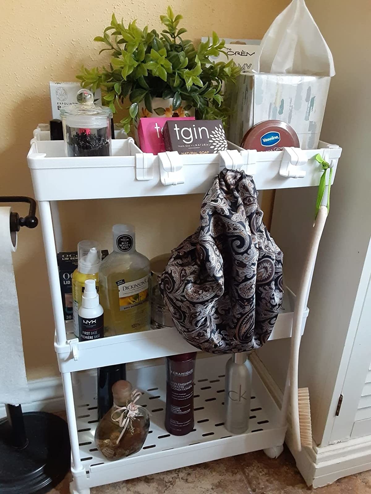 A cart in a reviewer&#x27;s home full of various shapes and colors of beauty products
