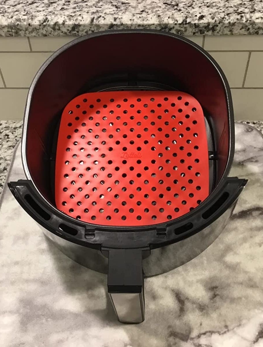 A reviewer showing the red liner inside of their air fryer