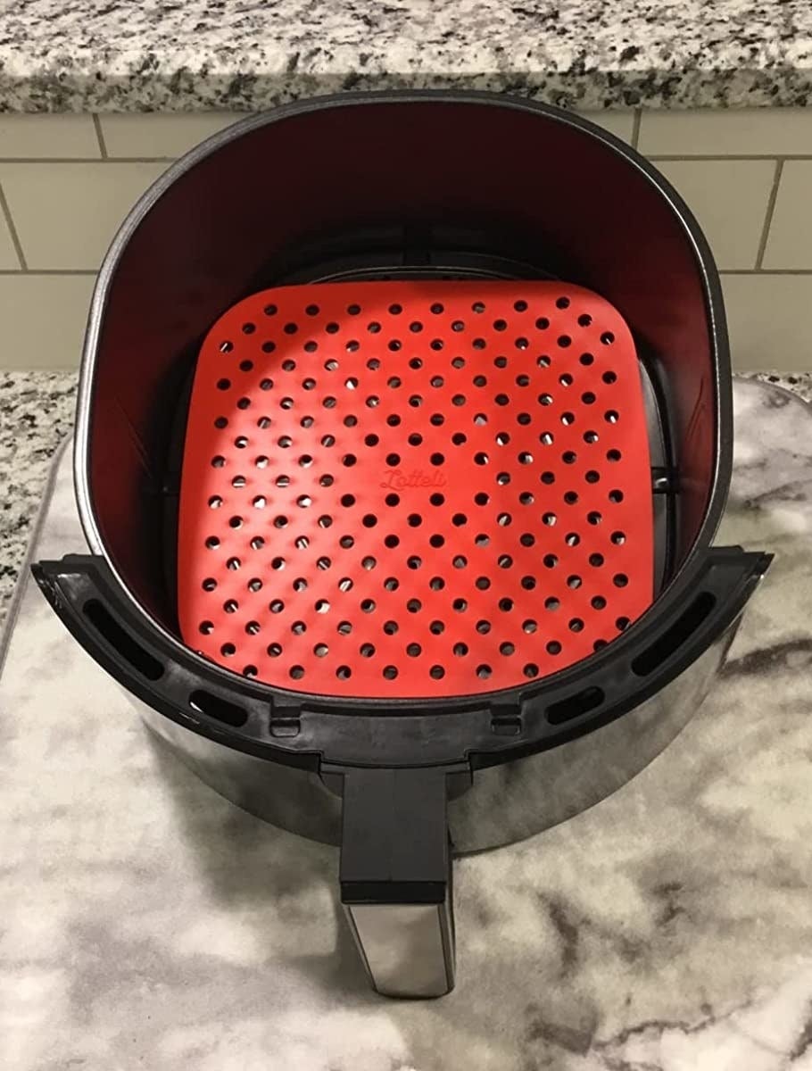 A reviewer showing the red liner inside of their air fryer