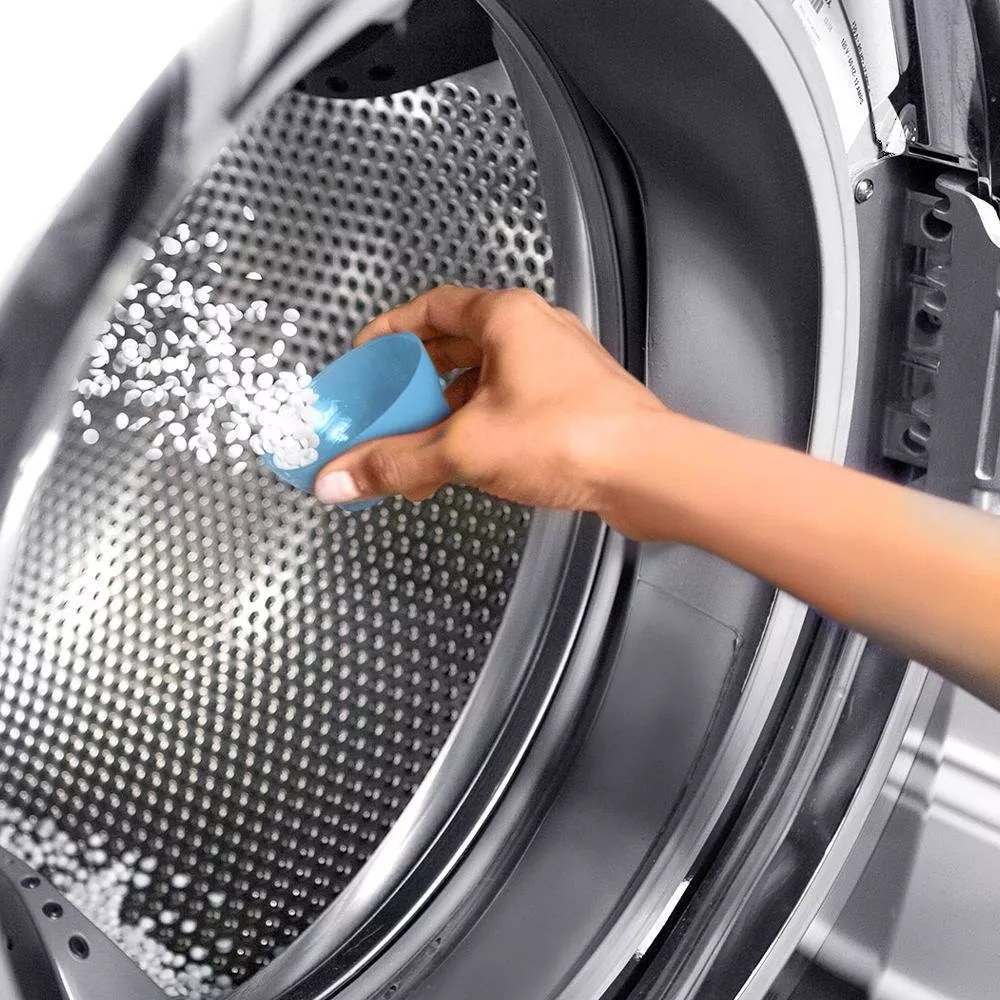 person adding the scent boosters to a load of laundry