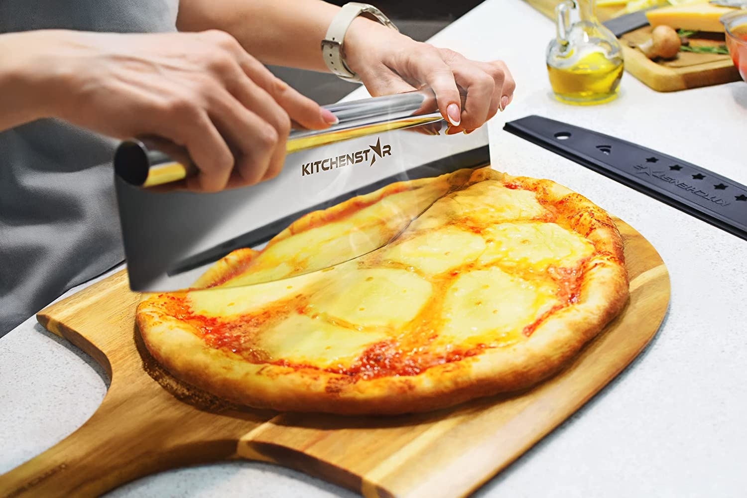 A person using the cutter to chop a pizza