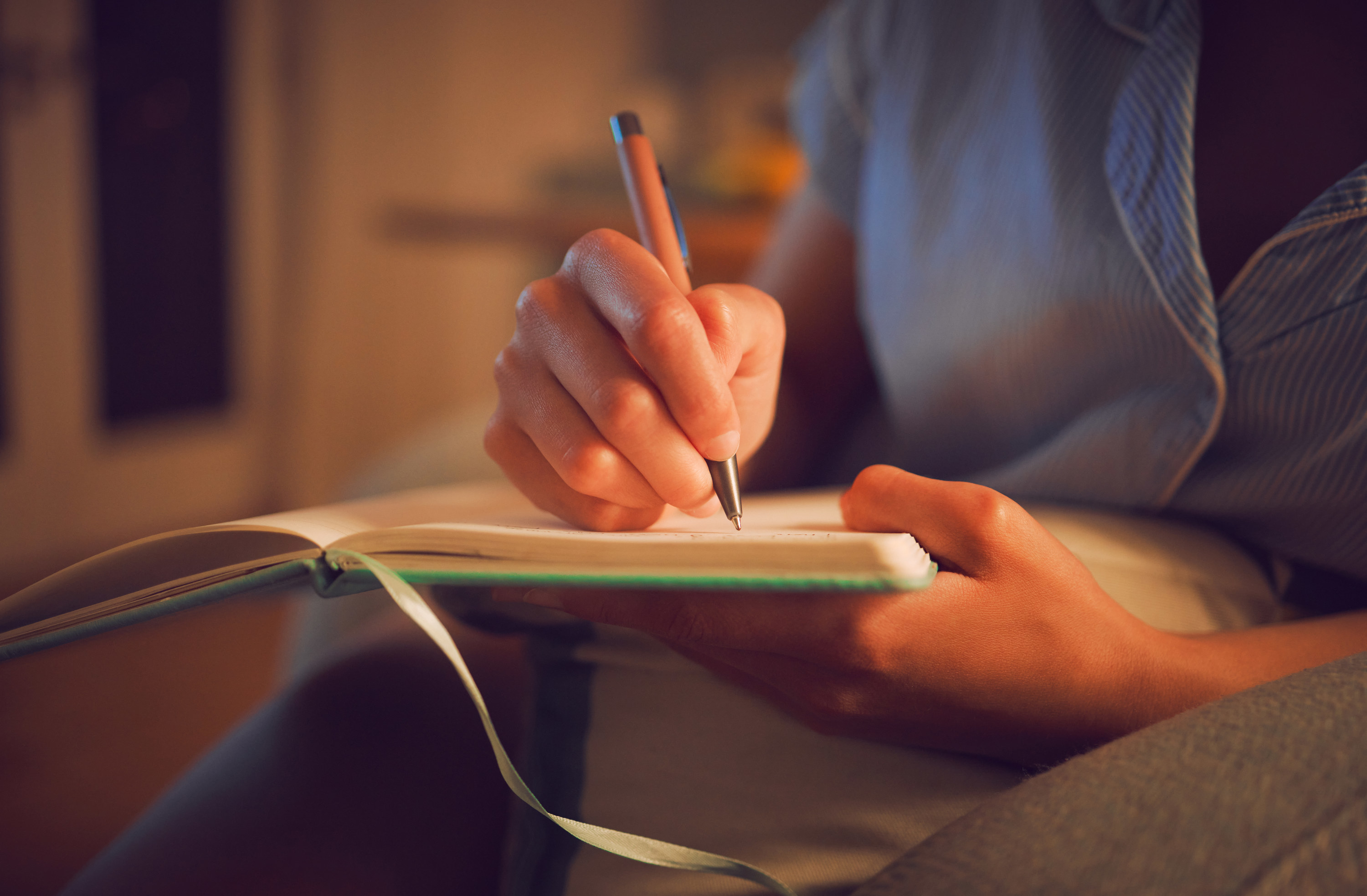 a hand holding a pen and writing in a journal