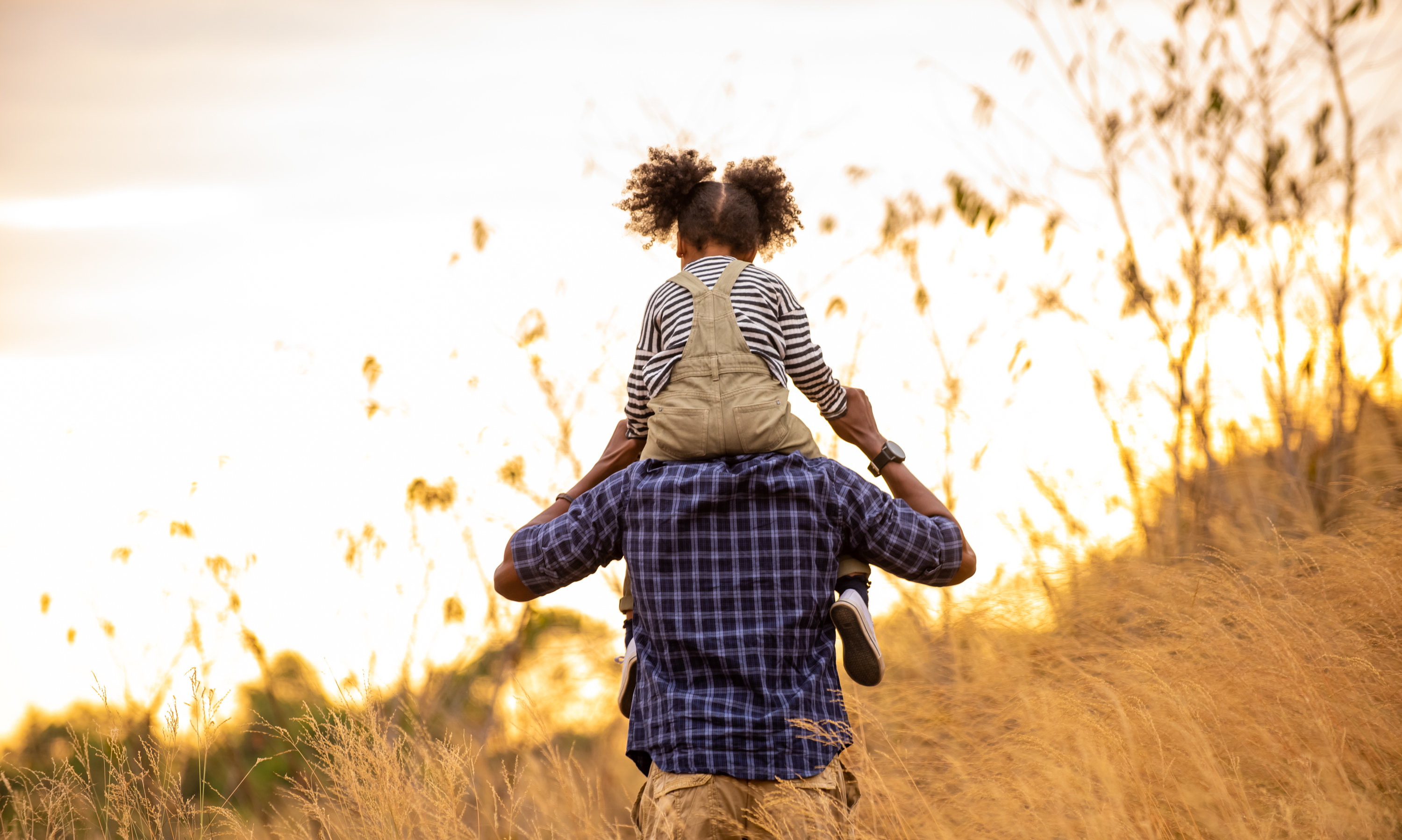 Kid riding on someone&#x27;s shoulders outside