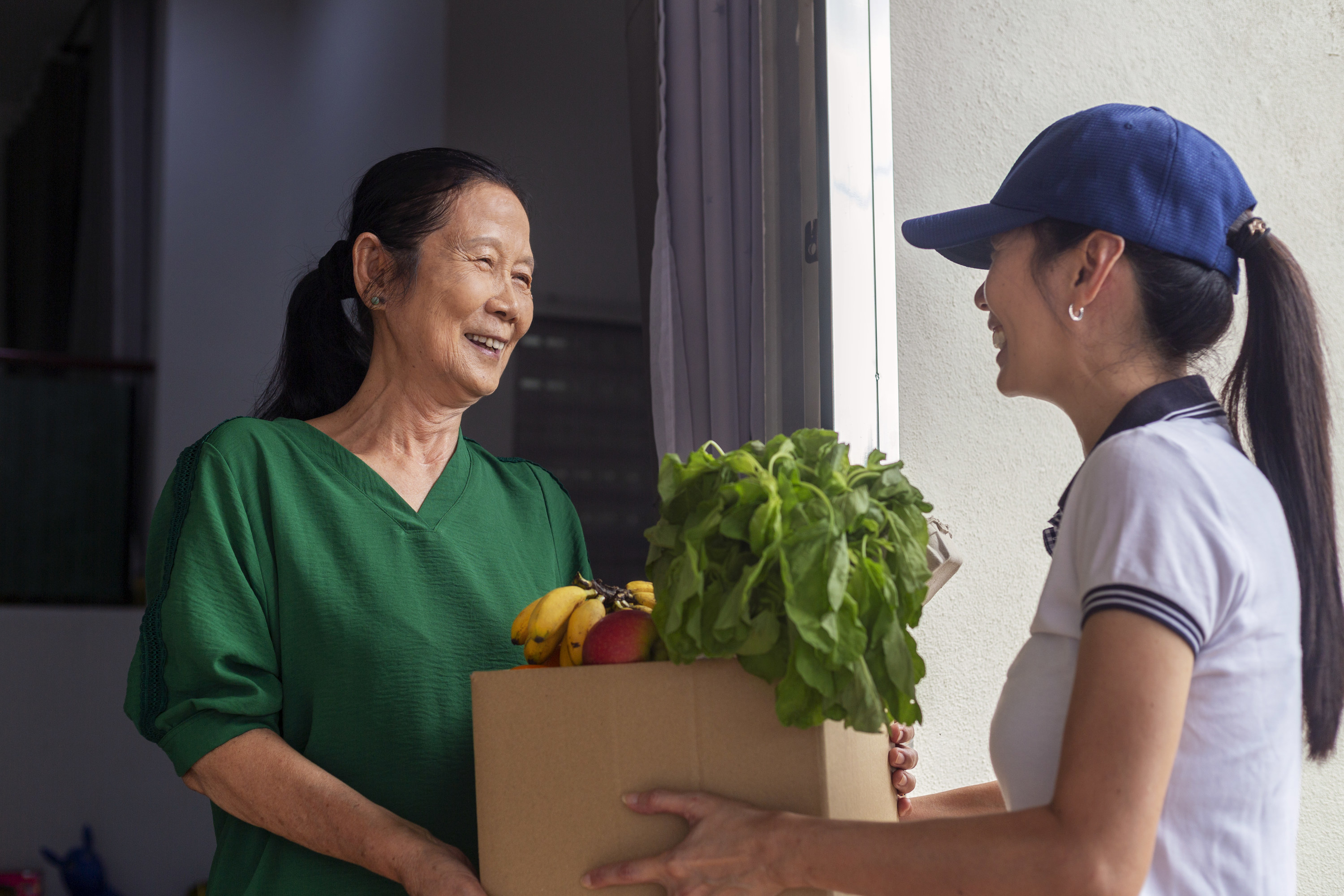 a woman handing a box of groceries to a person