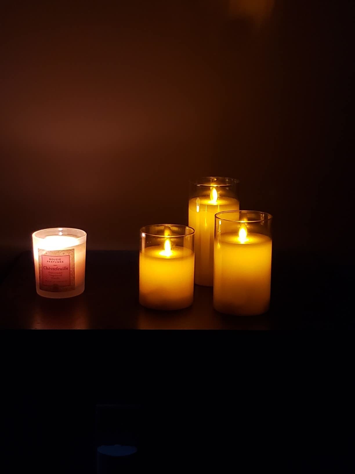 Reviewer&#x27;s photo of the LED pillar lights next to a real candle with identical looking flames