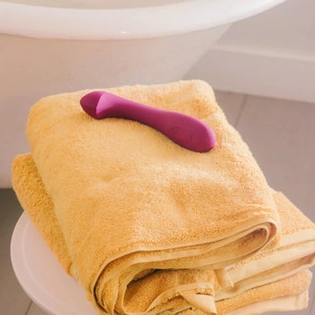 Purple vibrator on towel near bathtub
